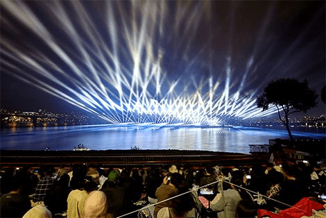 Crowds watching coordinated lights over the Han River during the Seoul fireworks festival